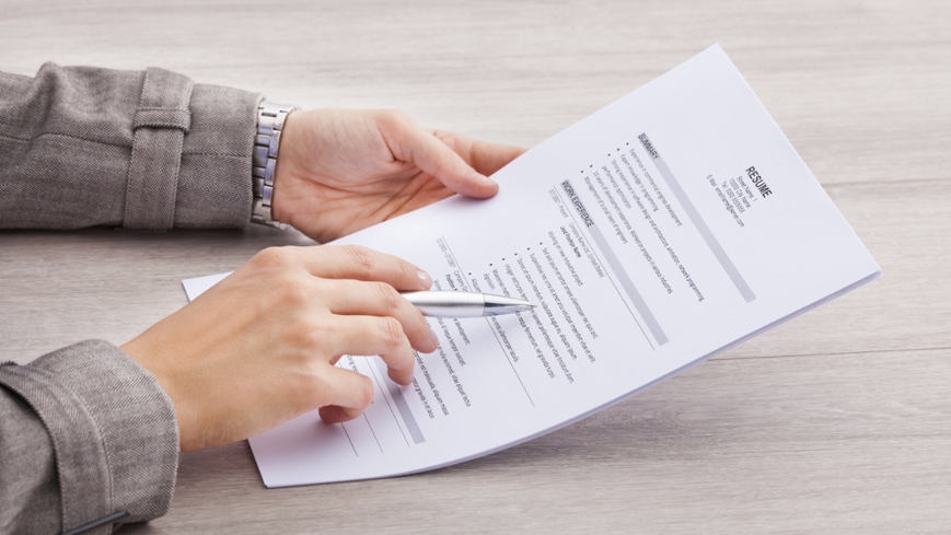 image of someone holding a Resume Sample Template and a pen
